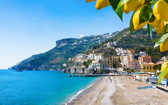 Scenic view of Minori town with sandy beach and blue sea water on Amalfi coast in Italy. Yellow lemons on branches frame beautiful Mediterranean landscape under sunny sky 