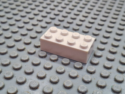 Single white plastic Lego construction brick placed on a textured studded building plate surface on December 19, 2025 in Bangkok, Thailand