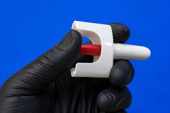 A 4K close-up image of a clinical professional in a black glove holding an emergency nasal spray device used for opioid overdose reversal against a blue background.