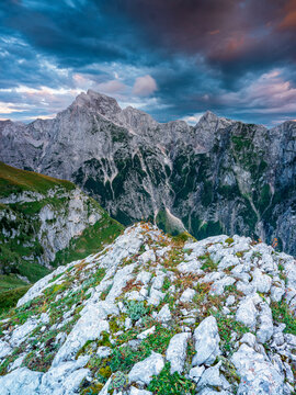Mountain landscape and rugged rocky terrain offer inspiration for adventure tourism and exploration under a dramatic sunset sky at Mangart, Julian Alps, Italy-Slovenia border.