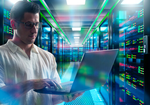 AI business technology. IT specialist works with laptop in data center server room managing cloud computing infrastructure
