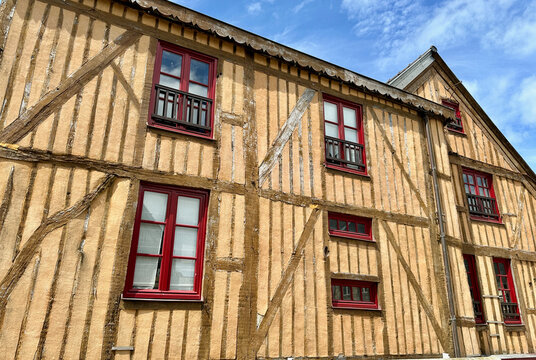 Old Rustic Half-Timbered French Building Facade with Beige-Yellow Infill and Red Window Frames