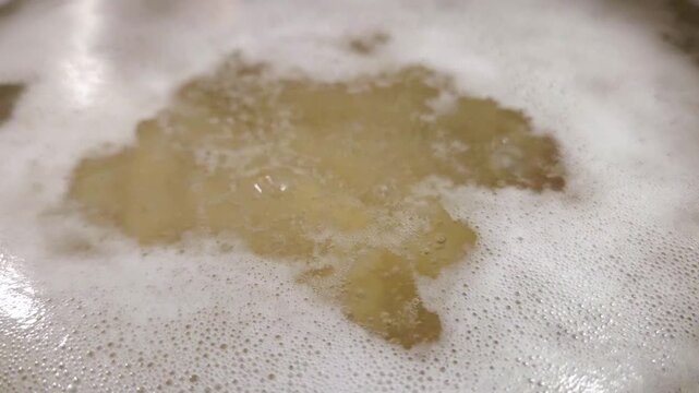 Boiling pasta in a pot with bubbling water and foam, showing gradual changes in texture and color as the cooking process progresses