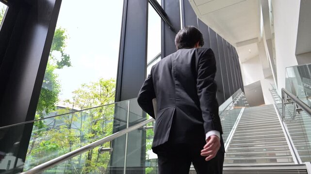 [スローモーション]オフィスで階段を上る、歩く若い新卒のようなビジネスマンの営業イメージ　未来や目標、スタートする頑張るイメージの動画　後ろ姿の顔無し広角