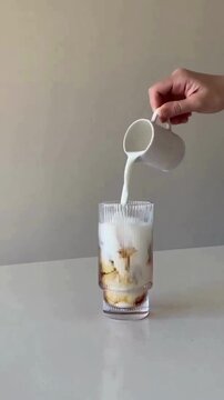Pouring Creamer Milk into Black Coffee in Glass Cup with Aesthetic Swirl Mixing Effect