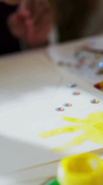 Female Hand Painting on Canvas Paper with Yellow Paint in Creative Art Workspace