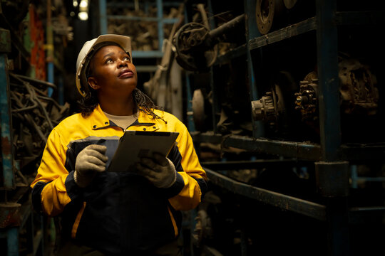 African female engineer checking auto parts inventory with a tablet in warehouse