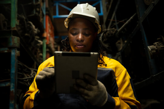 African female engineer checking auto parts inventory with a tablet in warehouse