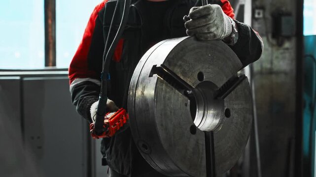 Experienced Worker Carefully Directs Overhead Crane To Position Steel Component Into Machine With Safety Focus
