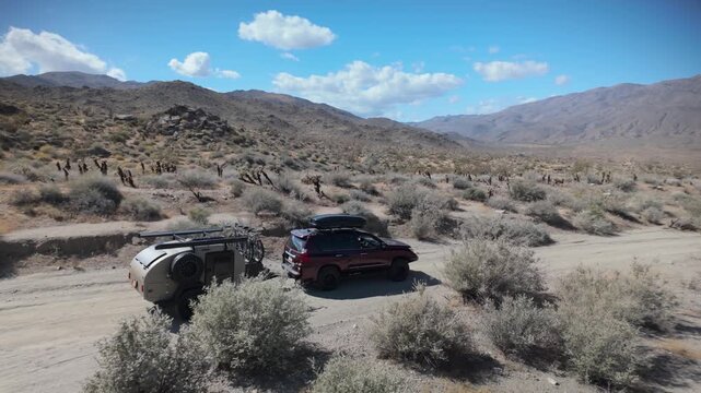 Aerial views show a teardrop camper and SUV navigating trails in Anza Borego Desert and Prune Canyon in California.