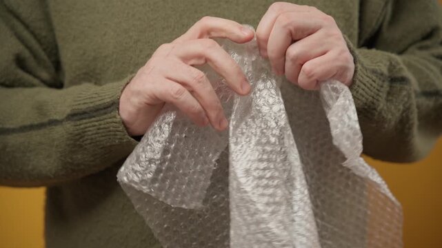 hands squeezing and popping plastic bubble wrap for stress relief.