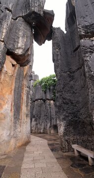 Legendary limestone boulder wedged precariously between two towering karst walls, known as 'Close Call' (Geng Xian), creates outstanding spectacle at Shilin Stone Forest. Vertical POV shot