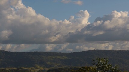 Fototapeta premium Large White Cumulus Clouds Floating Over Lush Green Rolling Hills