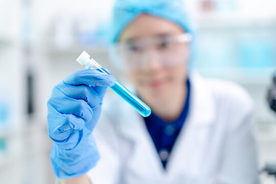 hand of scientist hold test tube beaker with liquid chemical water to recheck experiment result in laboratory, doctor with blue glove research analyze biochemistry for healthcare medical innovation