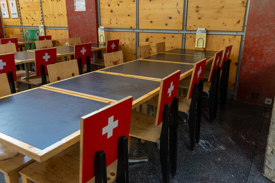 View of the interior of a traditional restaurant featuring wooden tables and chairs decorated with the Swiss flag in Gruyeres, Fribourg, Switzerland.