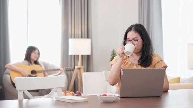 Two people at home, one working on a laptop while drinking coffee and the other playing acoustic guitar in a cozy living room. Promotes balanced lifestyle, creativity, companionship, and modern living