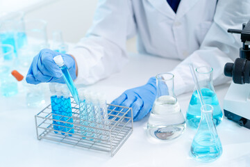 Fototapeta premium hand of scientist hold test tube with liquid chemical water to recheck experiment result in laboratory, doctor with blue glove research and analyze biochemistry for healthcare and medical innovation