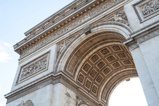 View of the Arc de Triomphe showcasing intricate stone carvings, classical reliefs, and the detailed coffered ceiling under a clear sky in Paris, Ile-de-France, France.