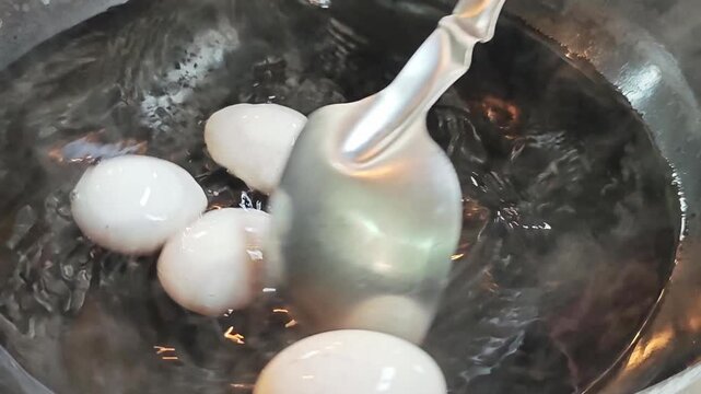 Process of boiling duck or chicken eggs in a pan, kitchen action shot.