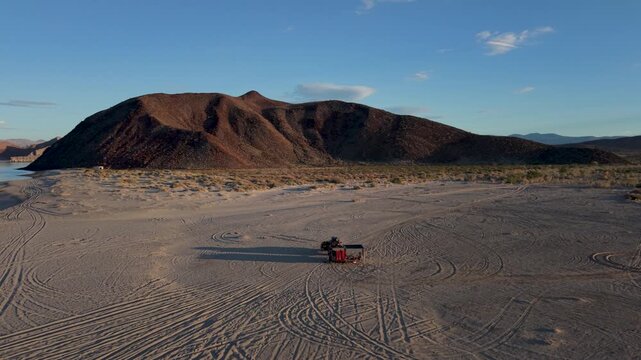 An SUV and teardrop trailer sit on the beach in Baja California Mexico during sunset.