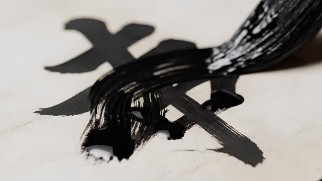 Closeup of a brush painting a Chinese character with black ink.