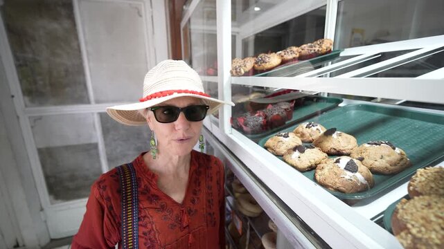 Mature woman visits a bakery in Santa Rosalia, Baja California, and looks at different types of pastries and treats available.