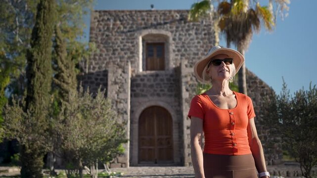 Mature woman visits Mission Santa Rosalia in Mulege surrounded by palm trees and mountains in Baja California Sur, Mexico.