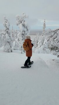 Experience the tranquility of Akaslompolo as a lone traveler explores a winter wonderland in snow shoes. Surrounded by snow-laden trees and a pristine white landscape, adventure beckons in Lapland.