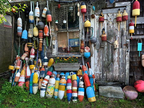 View of a rustic wooden fishing shack adorned with a vibrant collection of colorful buoys and nautical nets in Edgartown, Massachusetts, United States.