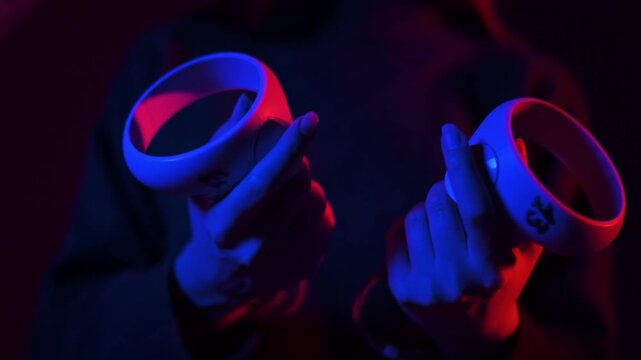 Person holding virtual reality controllers in dark room with cinematic red and blue lighting.