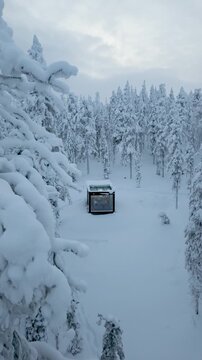 Discover a secluded cabin blanketed in fresh snow, nestled among tall trees in the enchanting winter landscape of Akaslompolo, Lapland. A tranquil retreat in a winter wonderland awaits.