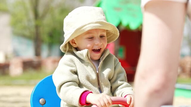 Child enjoys playtime on a swing set at the park in spring