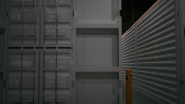 Moody shot inside an industrial storage yard with a large white shipping container unit opening into shadow. Great for logistics, moving, mystery, and warehouse background shots.