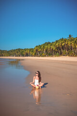 Obraz premium Woman meditating on tropical beach with coconut drink