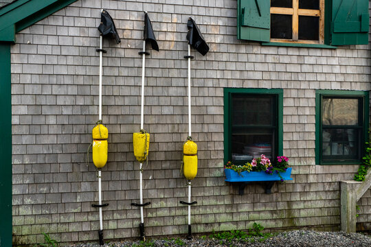 View of yellow fishing buoys on poles against a weathered cedar shingle wall at Martha's Vineyard in Edgartown, Massachusetts, United States.