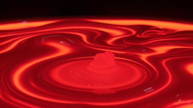 Abstract red liquid surface with vibrant glowing waves and smooth reflective patterns