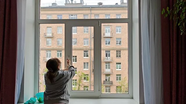 Woman closing a clean window after housekeeping. Fresh air, spring cleaning routine, tidy home, satisfying moment of completed chores.