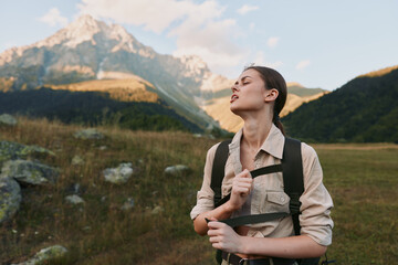 Fototapeta premium Young woman with brunette hair enjoys a peaceful moment hiking in the mountains during golden hour with a relaxed expression and casual outdoor clothing.