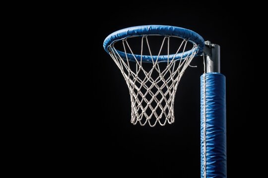 Isolated netball hoop with blue padded rim and nylon mesh net on metal pole against black background for sports fitness concepts