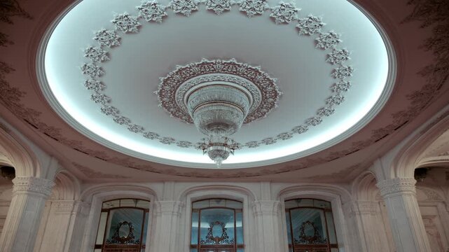 Grand interior of historic palace featuring crystal chandelier and ornate neoclassical architectural details in Bucharest.
