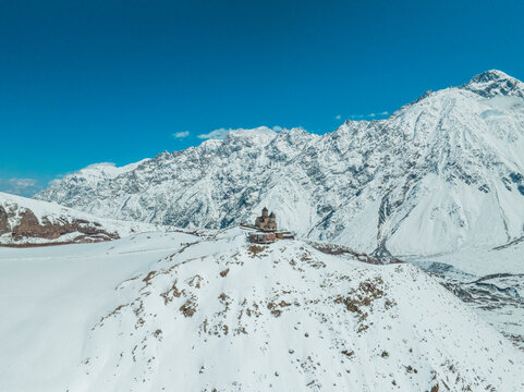 Drone View of Gergeti Church Surrounded by Snowy Mountains