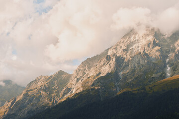 A lone hiker gazes at rugged mountain peaks as clouds drift above a sunlit valley, capturing a calm outdoor moment of nature, solitude, and self reflection © SHOTPRIME STUDIO