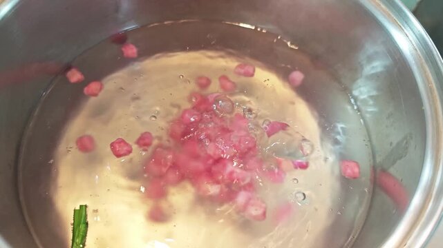 Close-up of boiling water chestnut cubes covered in tapioca starch for Thai dessert.