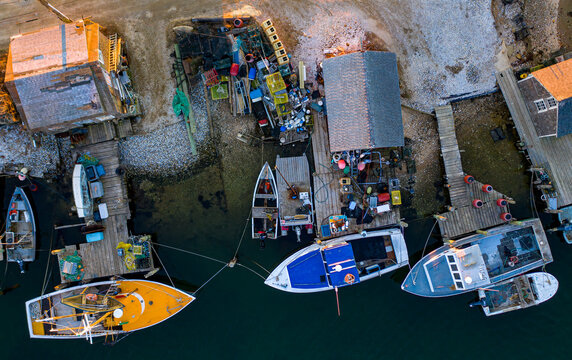 View of fishing boats moored at wooden docks next to rustic shacks on Martha's Vineyard with lobster traps and gear in Edgartown, Massachusetts, United States.