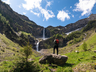 Naklejka premium Hiker standing on rock admiring mountain waterfall landscape
