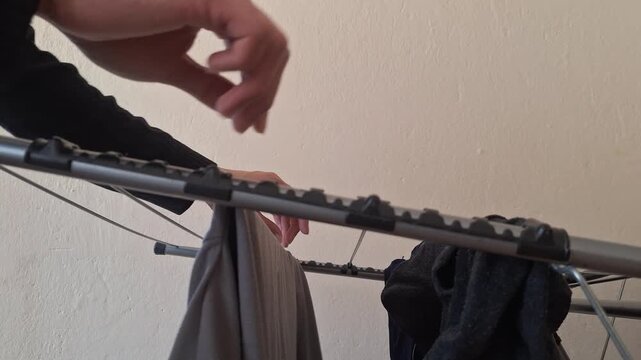 Person adjusts clothing on a drying rack