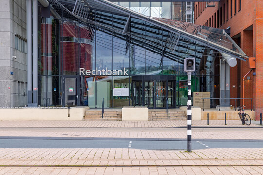 Rotterdam, Netherlands, 16 May 2026. The modern glass entrance facade and revolving doors of the Rotterdam District Court courthouse building with a bicycle parked nearby.
