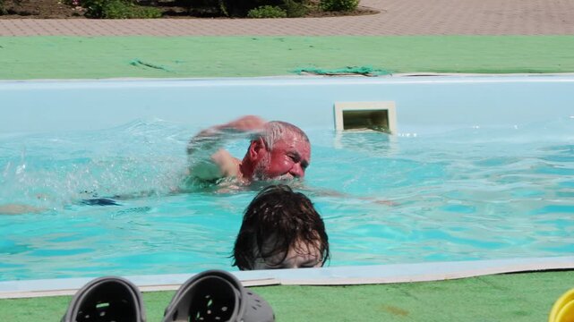 Swimmer practices in pool with observer during sunny afternoon