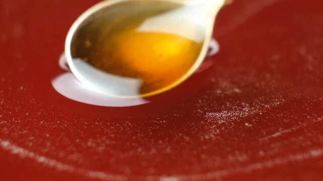 Macro slow motion of natural maple syrup dripping from spoon