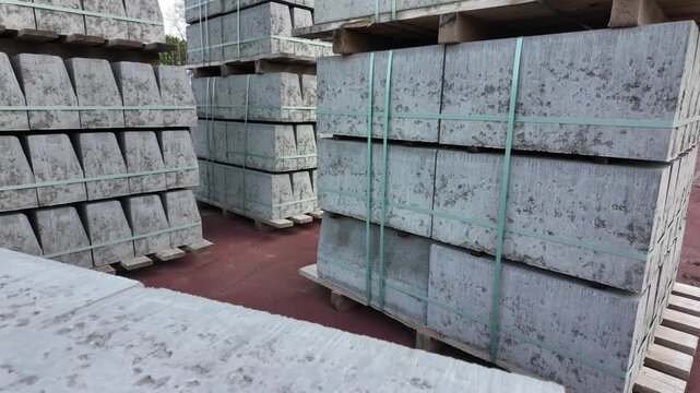 Video of stacked concrete slabs on wooden pallets at a construction materials yard. Industrial building supplies prepared for transportation and construction use.